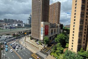A high-rise building with a prominent vertical design, adjacent to a busy street with vehicles and a pedestrian crossing. - Shankee Chain Hotel (Shenzhen Longhua Qinghu Subway Station) (Shenzhen)