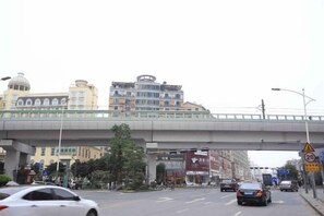 A multi-level urban street with a pedestrian overpass, vehicles, and buildings. - Shankee Chain Hotel (Shenzhen Longhua Qinghu Subway Station) (Shenzhen)