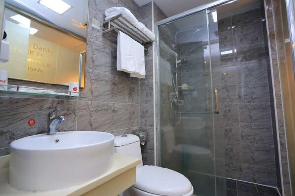 A bathroom with a glass-enclosed shower, a white sink, and a toilet.