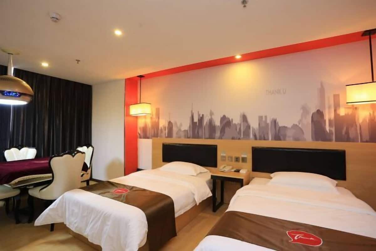 Une chambre d’hôtel avec deux lits, un bureau, une chaise et une fresque représentant un paysage urbain sur le mur.