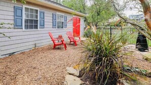 A house with a covered patio area, red Adirondack chairs, and a red door. - Fox Cottage *Pet Friendly* (Catonsville)
