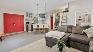 A modern living room with a sofa, a coffee table, and a dining area with chairs and a table. - Fox Cottage *Pet Friendly* (Catonsville)