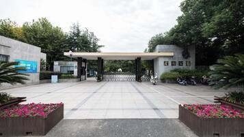 A gated entrance with a covered walkway, surrounded by flower beds and greenery.