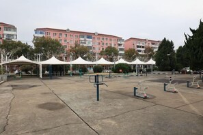 An outdoor exercise area with stationary bikes and a concrete surface, surrounded by white tents and trees.