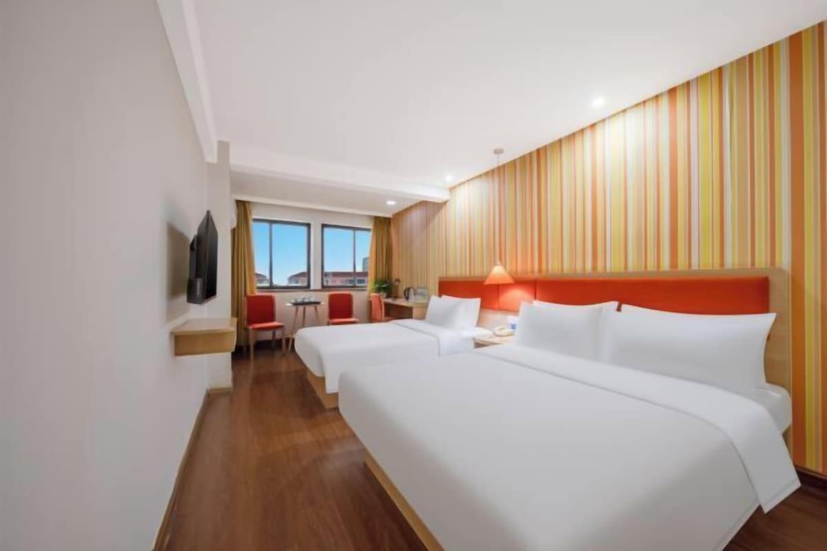 Ett hotellrum med två sängar, ett skrivbord, en stol och en TV.