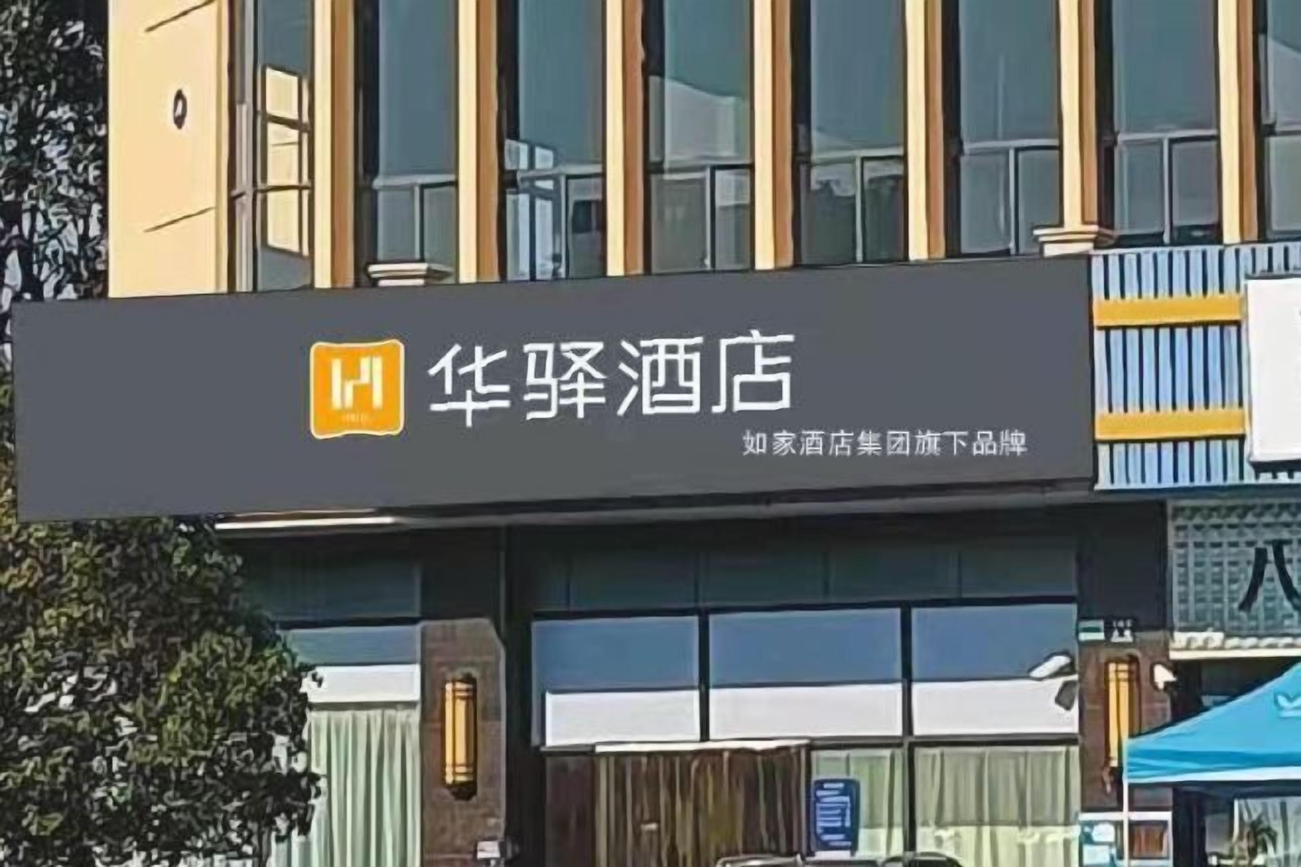 Une enseigne d’hôtel portant le nom « 华驿酒店 » et un logo.