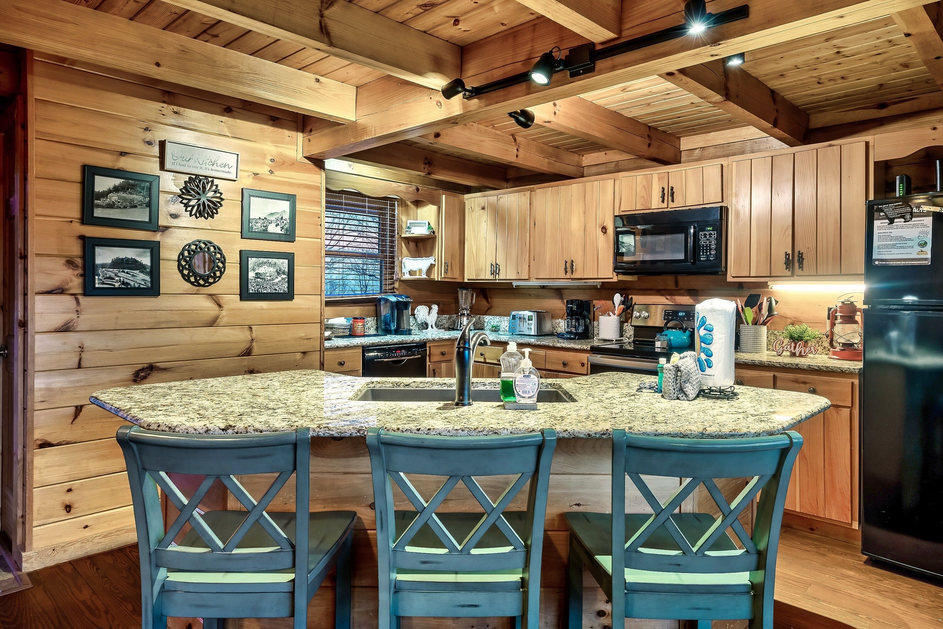 A kitchen with wooden cabinets, a granite countertop, and three blue chairs.