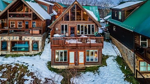 Un chalet en bois doté d’un balcon, de fondations en pierre et de nombreuses fenêtres.