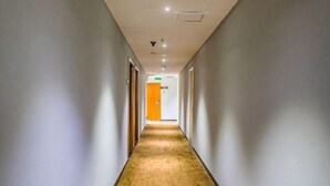 A long, narrow hallway with a carpeted floor, doors on both sides, and a ceiling with recessed lighting. - 7 Days Premium (Shenzhen Bao'an Bus Station Haiya Mega Mall) (Shenzhen)