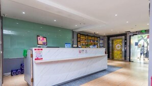 A reception desk with a digital screen, a green wall, and a tiled floor. - 7 Days Premium (Shenzhen Bao'an Bus Station Haiya Mega Mall) (Shenzhen)