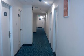 A hotel hallway with doors, carpeted floors, and a ceiling light. - 7 Days Premium (Shenzhen Bao'an Bus Station Haiya Mega Mall) (Shenzhen)