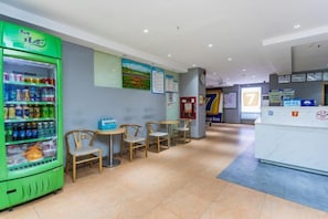 A hotel lobby with a vending machine, seating area, reception desk, and informational posters. - 7 Days Premium (Shenzhen Bao'an Bus Station Haiya Mega Mall) (Shenzhen)