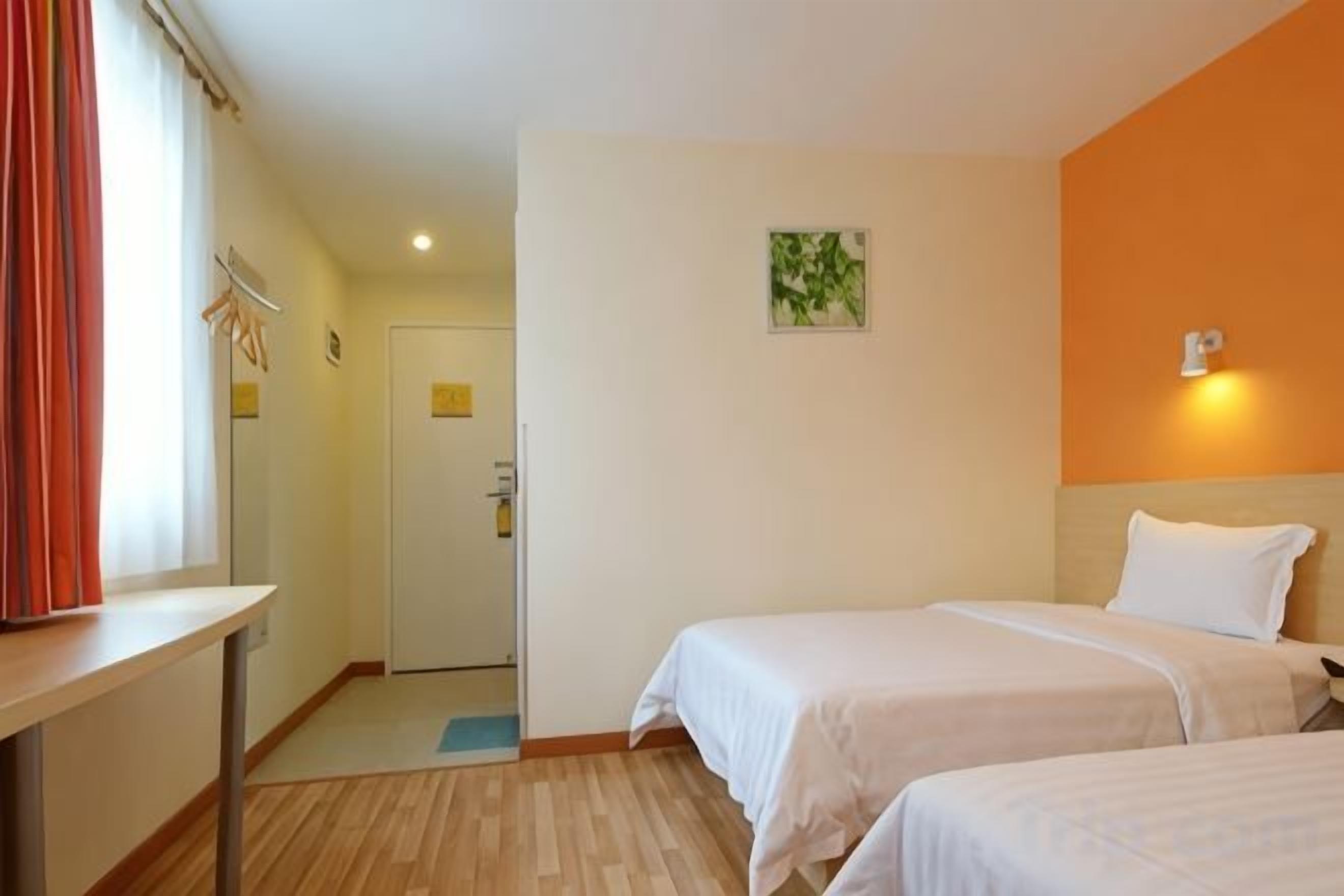 Ein Hotelzimmer mit zwei Betten, einem Schreibtisch und einer Tür zum Badezimmer.