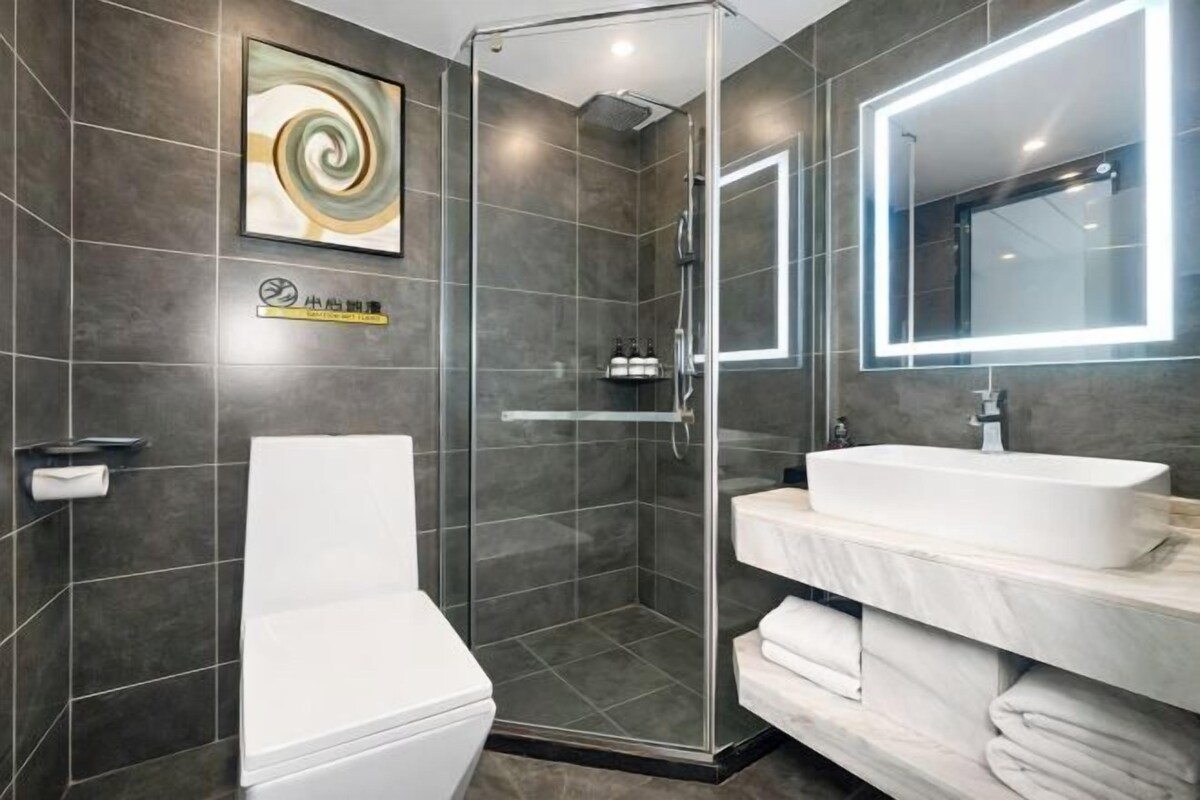 A modern bathroom with a glass-enclosed shower, a white toilet, and a vanity with a large mirror and two sinks.