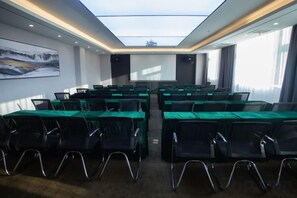 A conference room with a high ceiling, a projector screen, and rows of tables with chairs. - Feifan Boutique Hotel (Jiaozuo High-Speed Railway Station Wangfujing) (Jiaozuo)