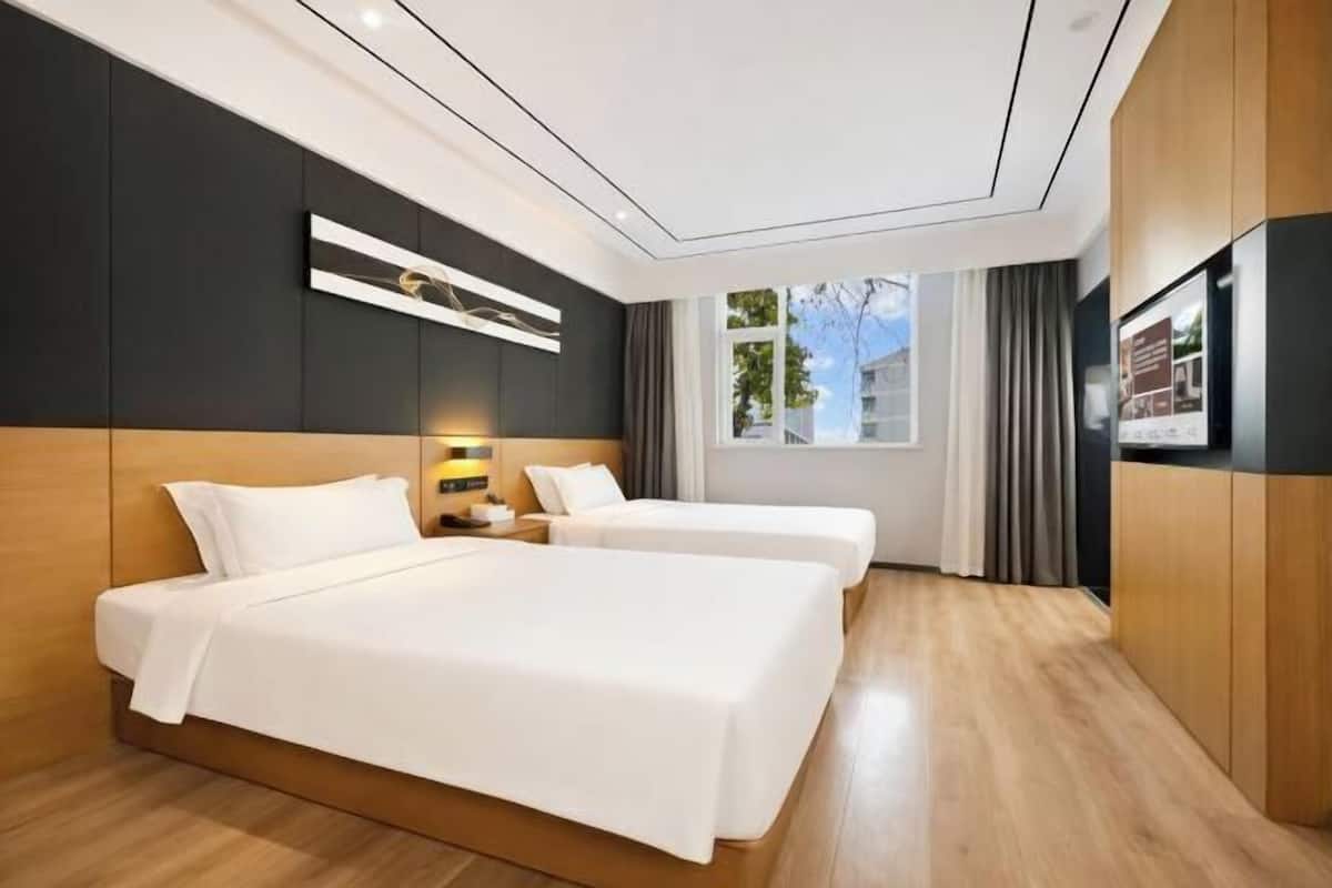 A modern hotel room with two beds, a large window, and a flat-screen TV.