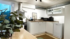 Une cuisine moderne avec des armoires blanches, un plan de travail en bois et une hotte de cuisine en acier inoxydable.
