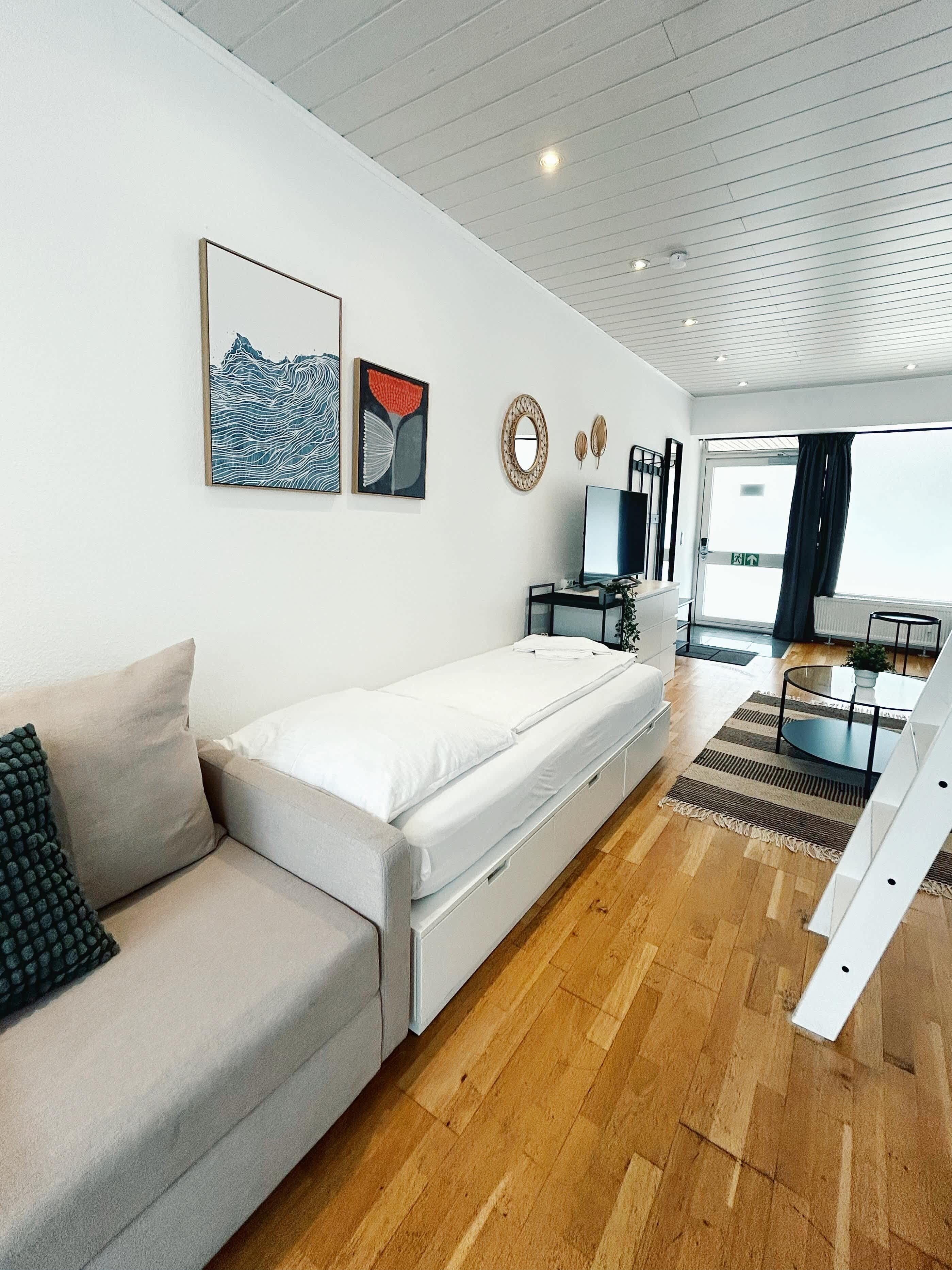 Ein modernes Wohnzimmer mit Sofa, Fernseher und Essbereich.