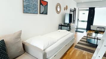 Ein modernes Wohnzimmer mit Sofa, Fernseher und Essbereich.
