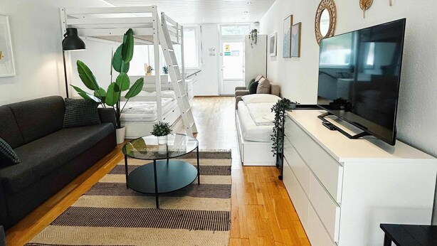 Un salon moderne comprenant un canapé, une table basse, un téléviseur et un escalier menant à une autre pièce.