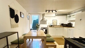 Un espace de vie compact comprenant un coin repas, une kitchenette et une table de baby-foot.