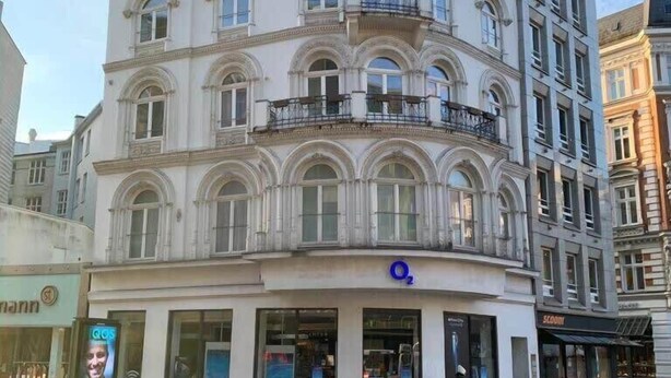 A multi-story building with a classical architectural style, featuring arched windows and balconies.