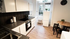 Una cocina moderna con armarios blancos, encimera negra y una mesa de comedor de madera con sillas.