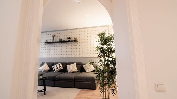 Una sala de estar con un sofá gris oscuro, una mesita de centro y una planta en maceta.