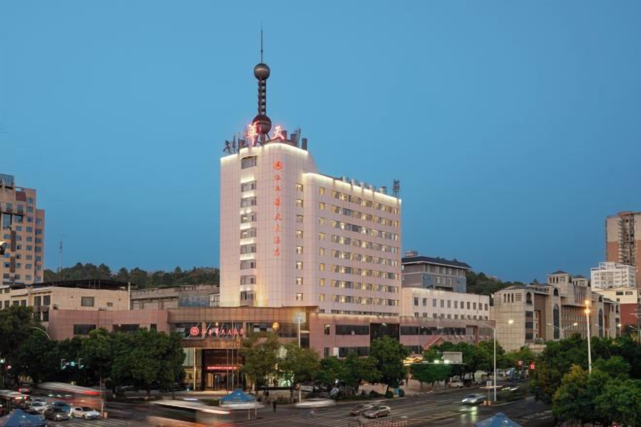 A multi-story hotel with a prominent tower and a spherical observation deck, surrounded by other buildings and a busy street.