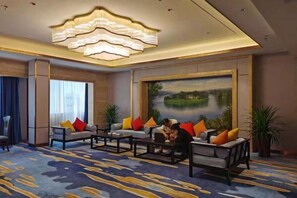 Un hall d’hôtel agrémenté d’un grand tableau, d’un lustre et d’un espace détente avec plusieurs canapés et une table basse.