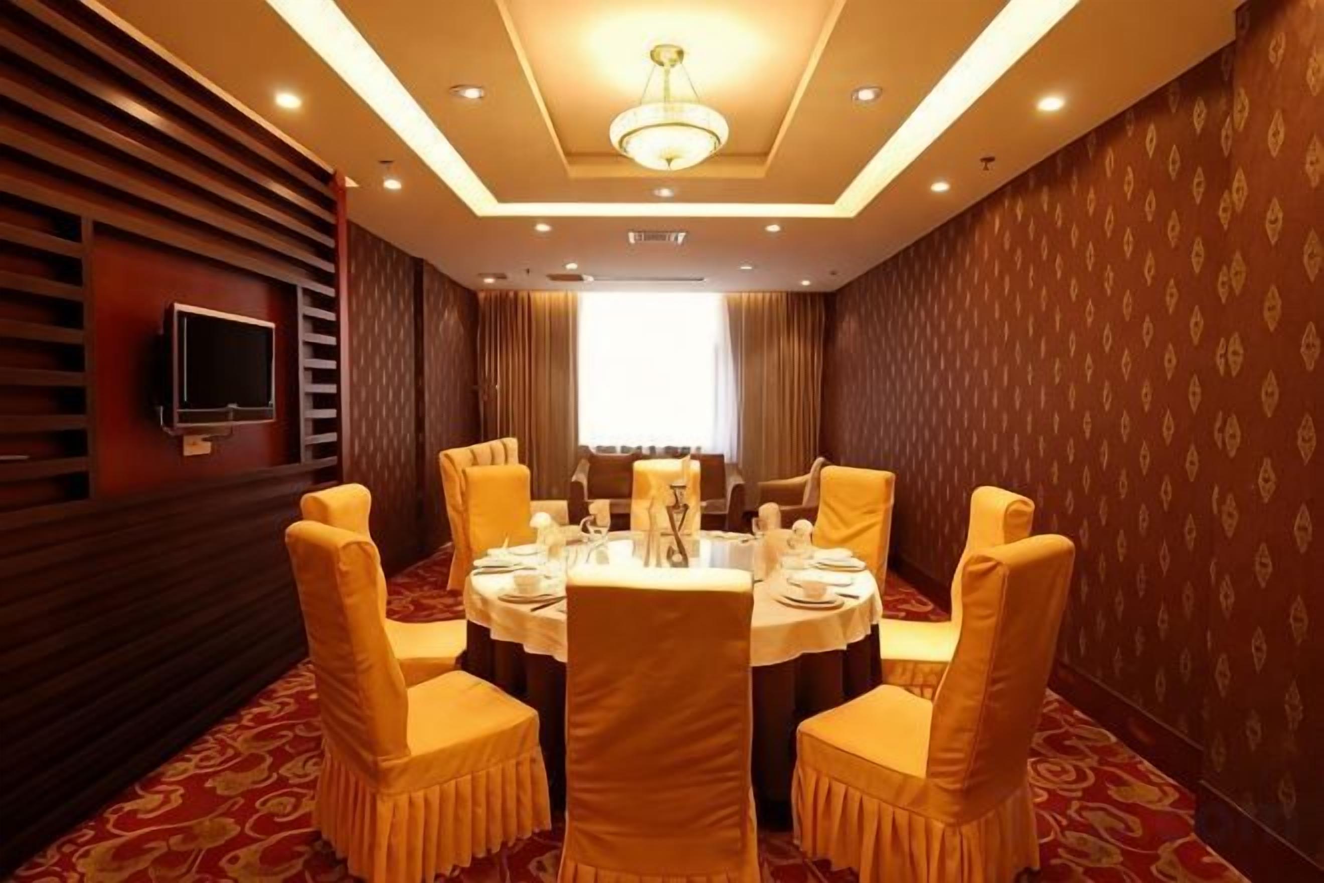 A conference room with a round table, chairs, and a television on the wall.