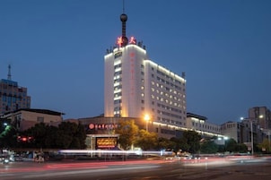 Un hotel de varios pisos con una torre destacada y señalización iluminada.