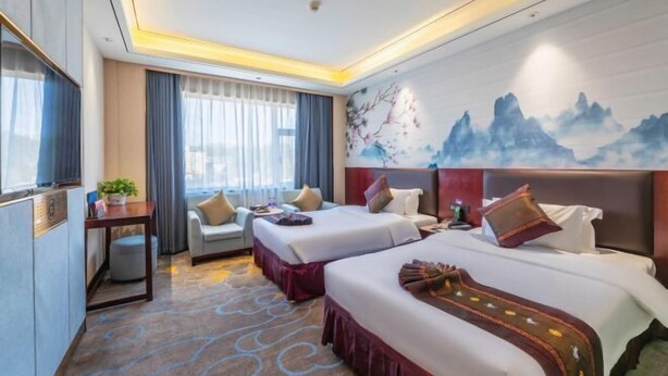 A hotel room with two beds, a sofa, a TV, and a painting on the wall. - Huafeng Huatian Hotel (Yongzhou)