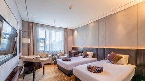 A hotel room with two beds, a desk, a chair, a TV, and a large window. - Huafeng Huatian Hotel (Yongzhou)