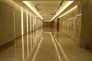 Un long couloir bien éclairé, doté de revêtements de sol réfléchissants et de portes des deux côtés.
