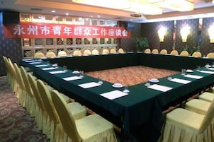 Un salón de conferencias con una larga mesa, sillas y un cartel.