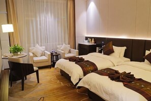 A hotel room with a large bed, a bedside table, a chair, a small table, and a plant. - Huafeng Huatian Hotel (Yongzhou)