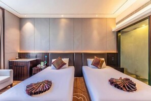A hotel room with two beds, a small desk, and a minibar.