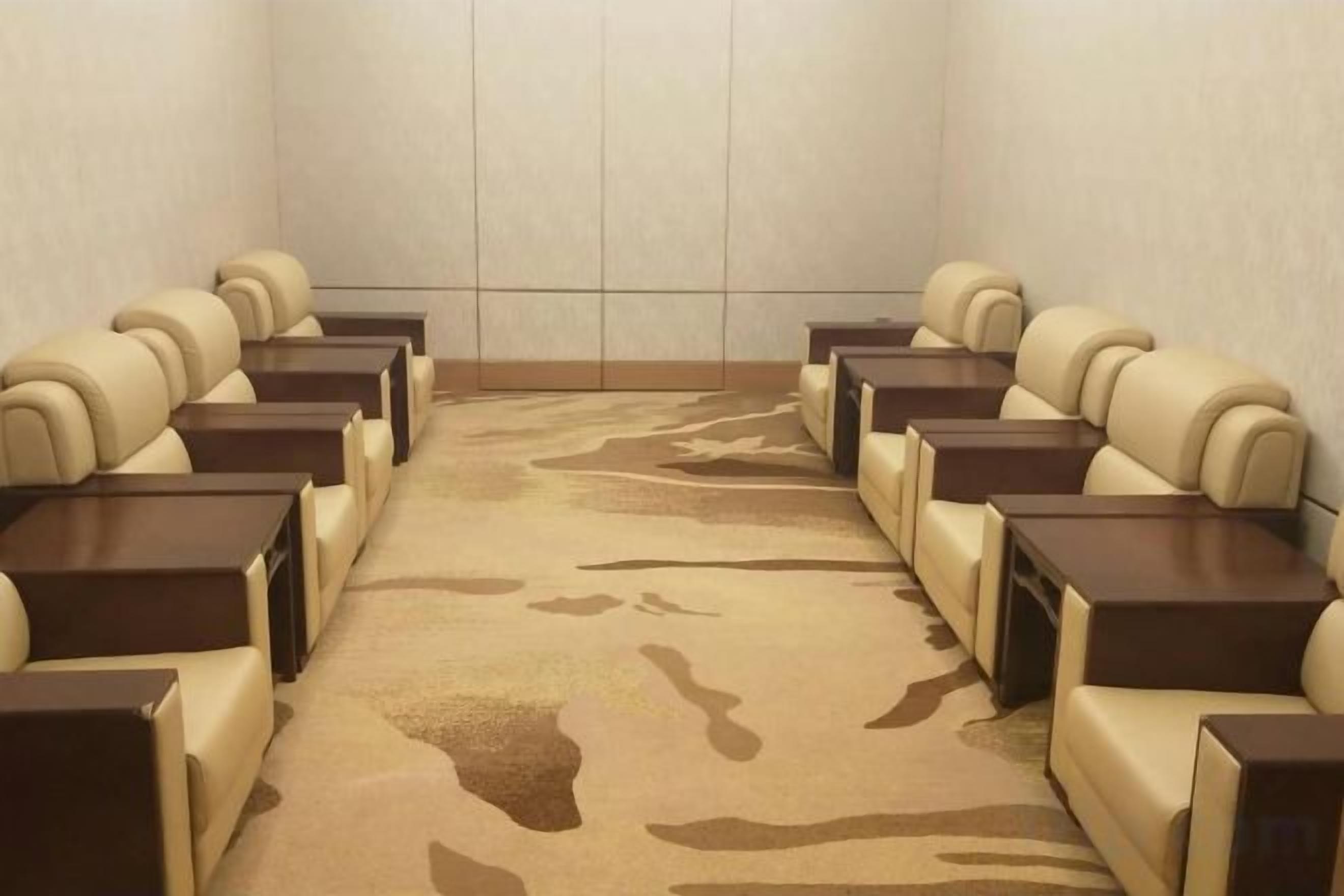 A conference room with rows of beige chairs and dark wooden tables.