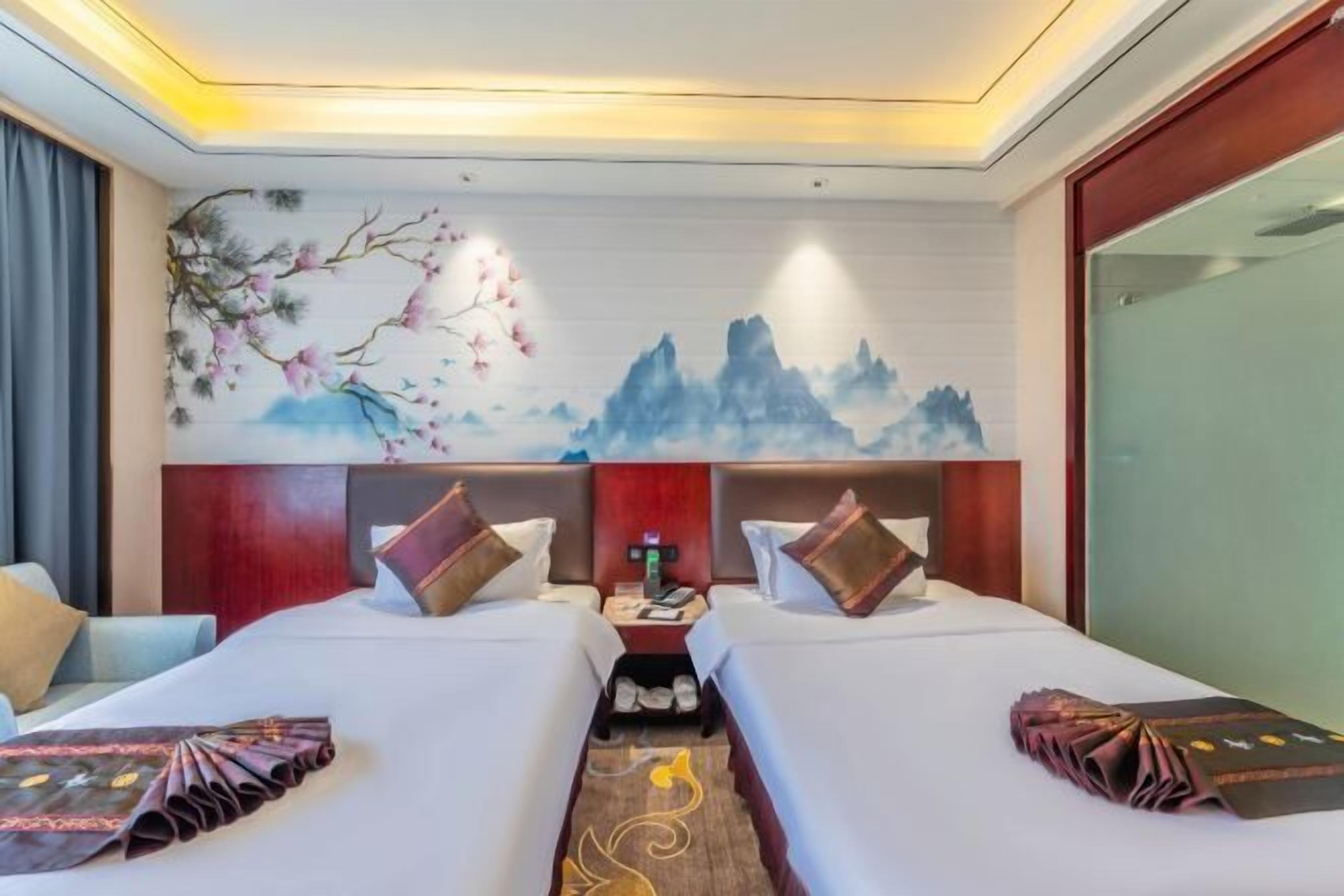 A hotel room with two beds, a nightstand, and a wall mural.