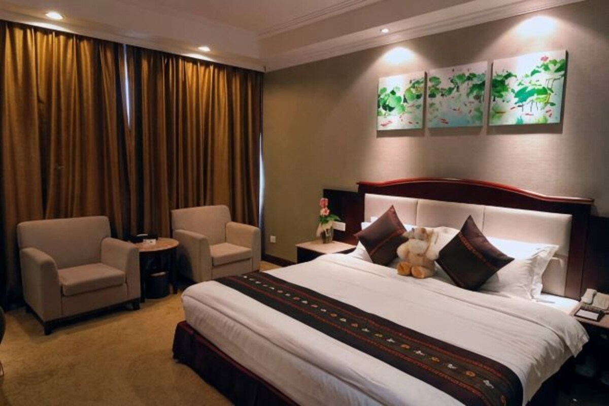 A hotel room with a large bed, two armchairs, a small table, and a nightstand.
