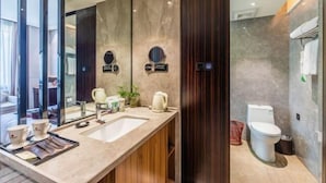 A modern bathroom with a large mirror, a sink, and a toilet. - Huafeng Huatian Hotel (Yongzhou)