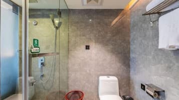 Un baño moderno con cabina de ducha de vidrio, inodoro y una silla roja.