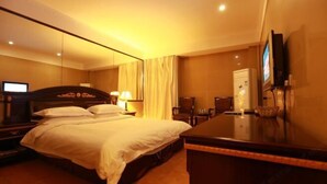 A hotel room with a large bed, a desk, a chair, a TV, and a minibar. - Laike Yangming Hotel (Chizhou)