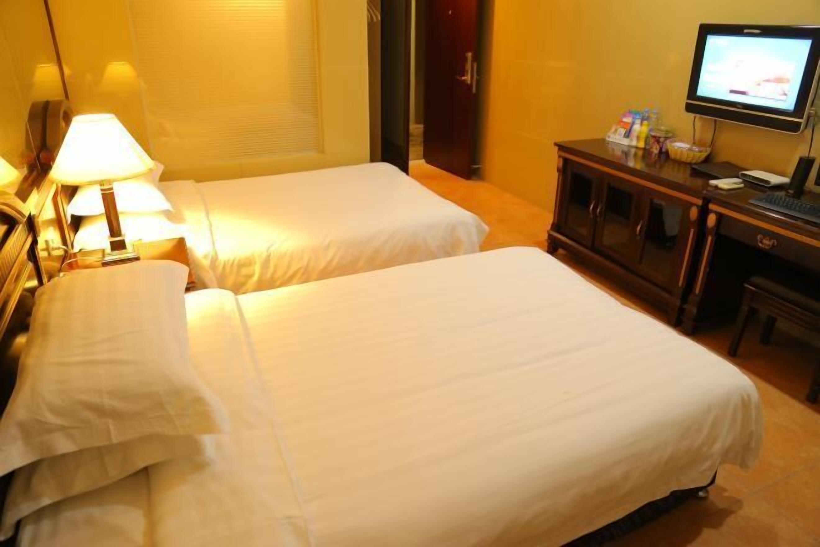 A hotel room with two beds, a desk with a computer, and a television.