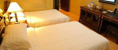 A hotel room with two beds, a desk with a computer, and a television.