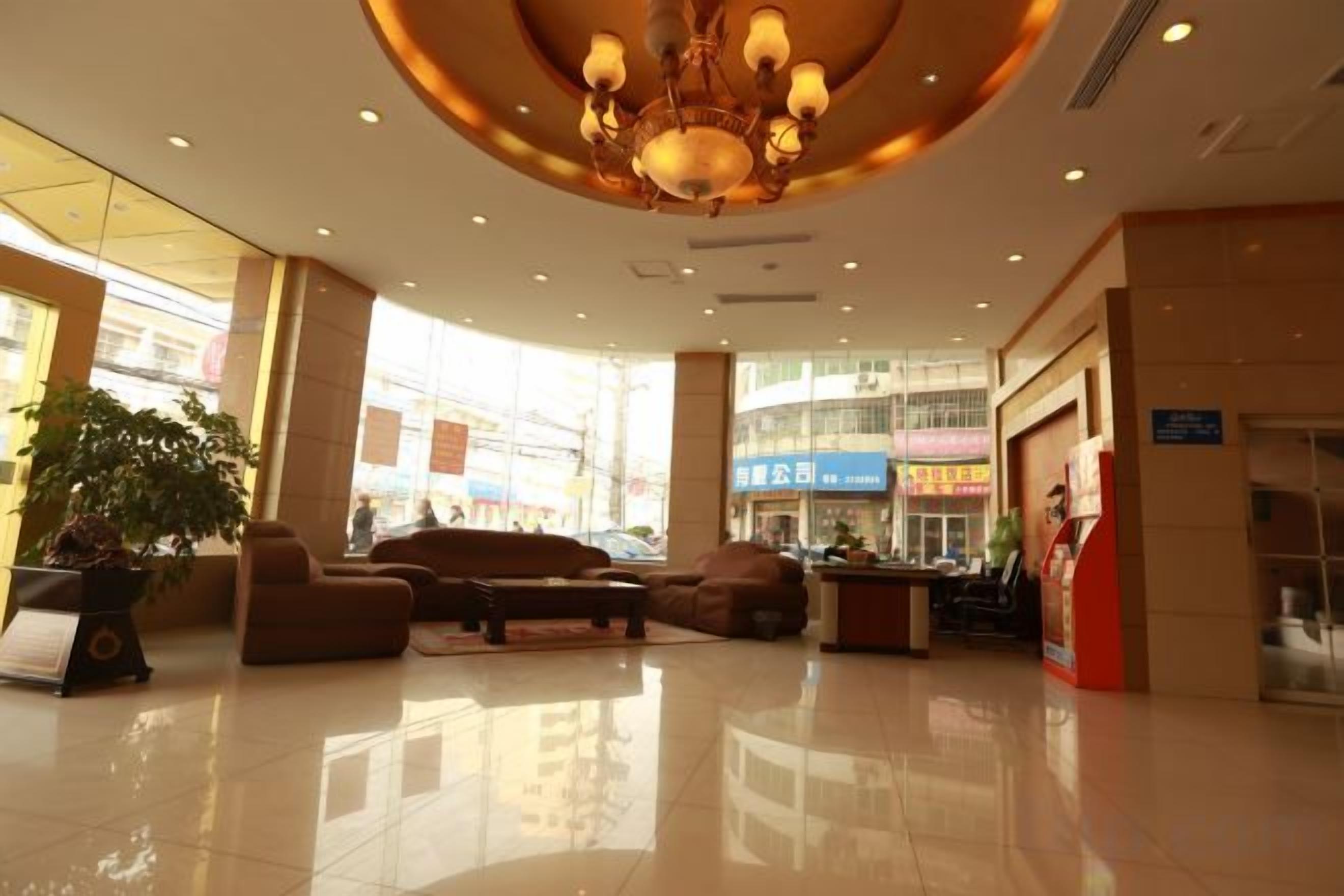 Un vestíbulo de hotel con candelabro, zona de estar y grandes ventanales.