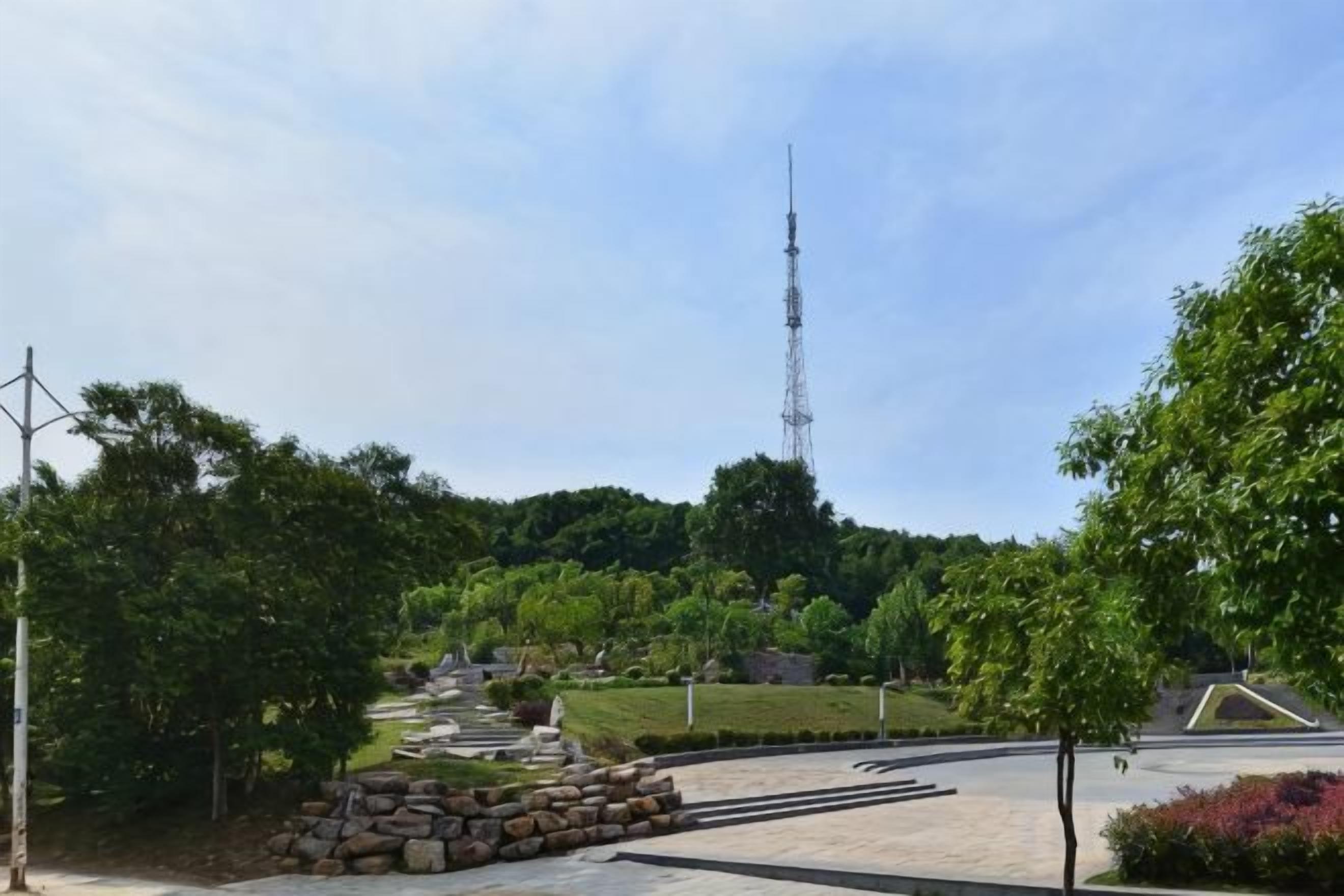A park with a pathway, trees, and a distant tower.