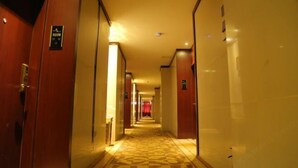 A hotel corridor with wooden doors, a patterned carpet, and a warm lighting ambiance. - Laike Yangming Hotel (Chizhou)