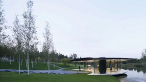 A modern building with a curved glass facade, surrounded by a well-maintained lawn and trees.